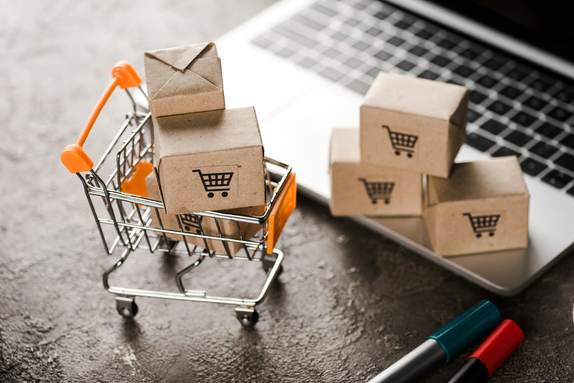 A small shopping trolley and parcels beside a laptop showing synchronized stock