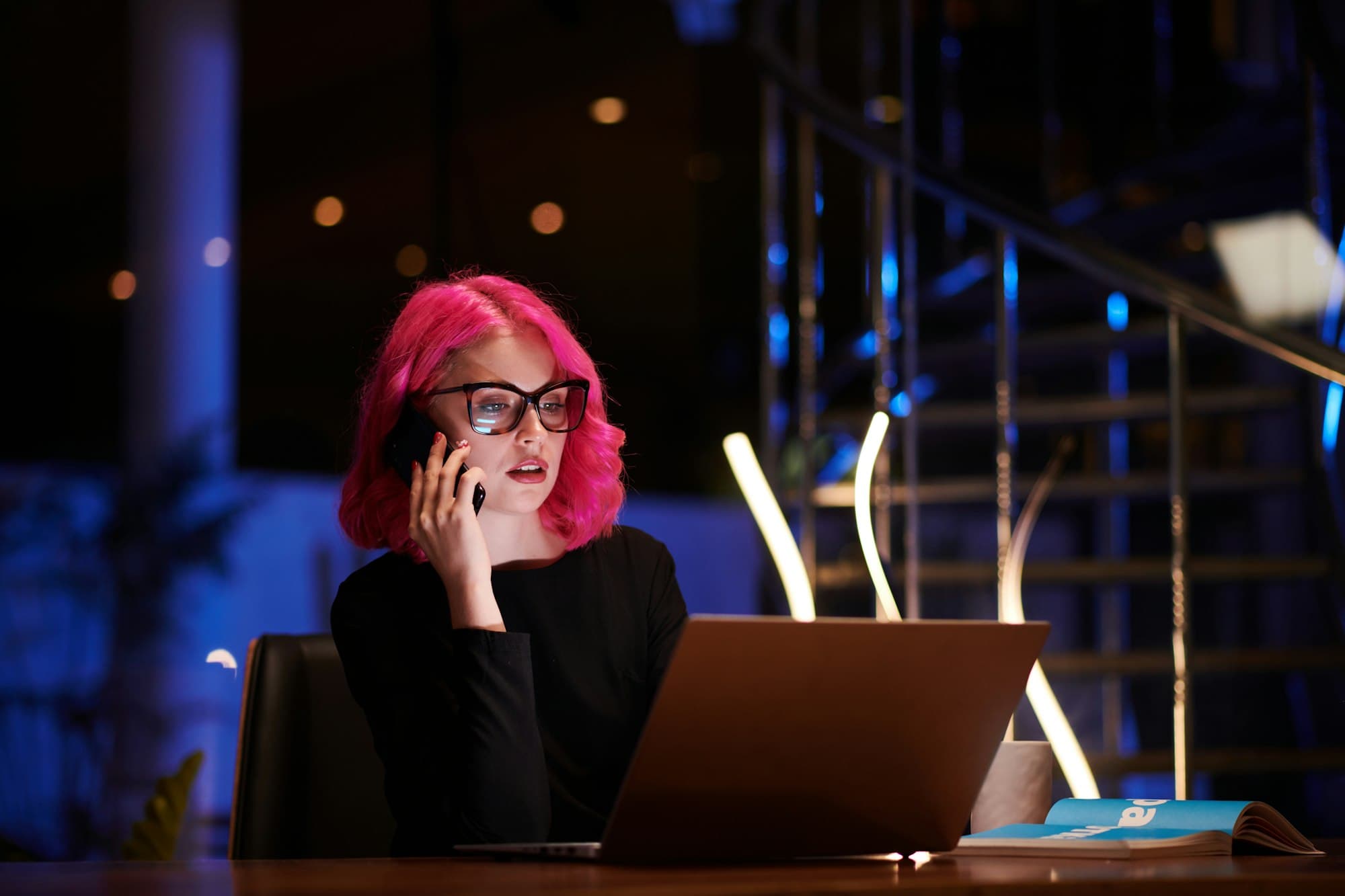 A businesswoman on the phone at her desk, laptop open in front of her