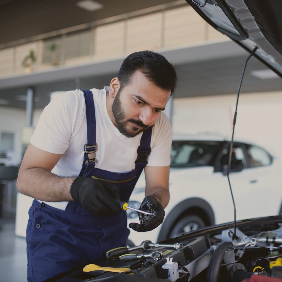 A mechanic checking an engine with the bonnet up