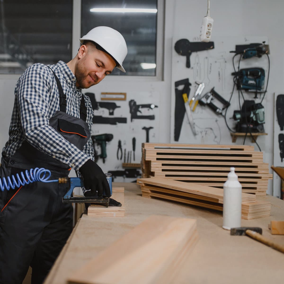 A carpenter using a nail gun on a timber frame