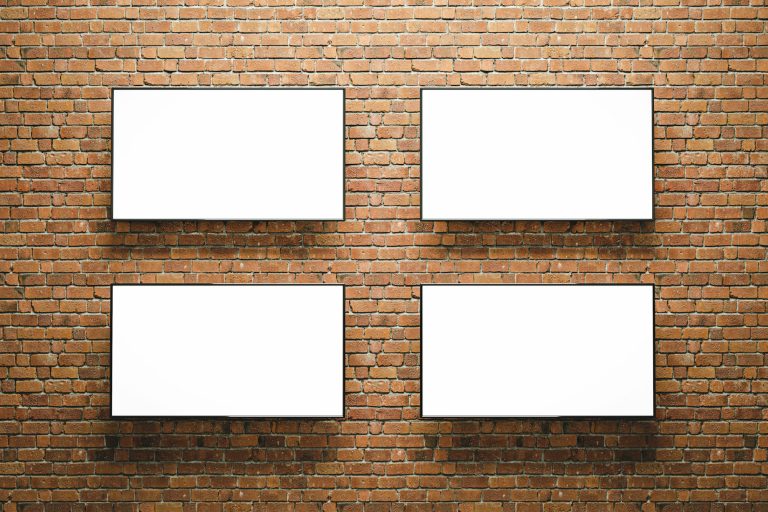 Four horizontal blank advertising posters or screens on bricks wall